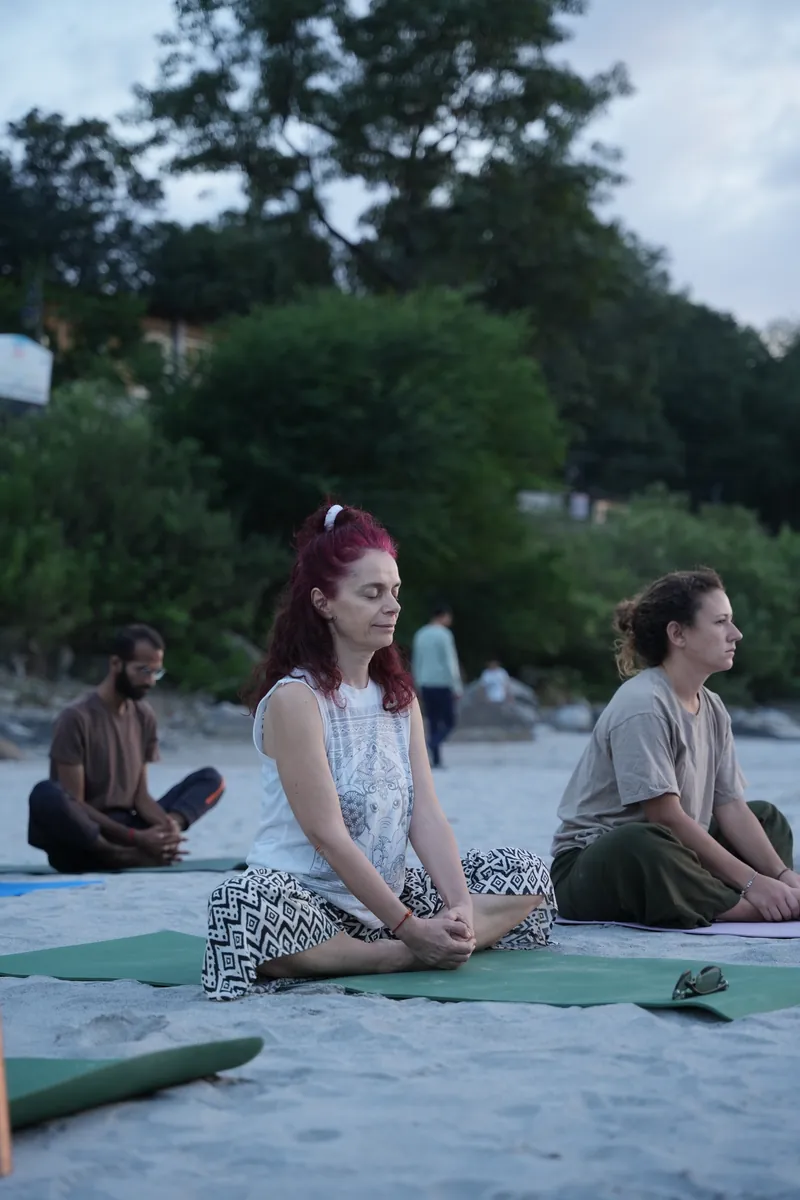 Yoga students practising together beside the river in Rishikesh