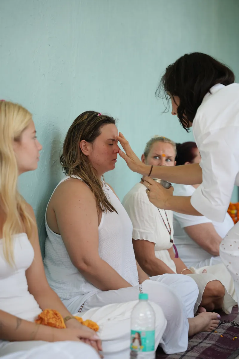 Teacher placing a garland on a graduating student during the closing ceremony in Rishikesh