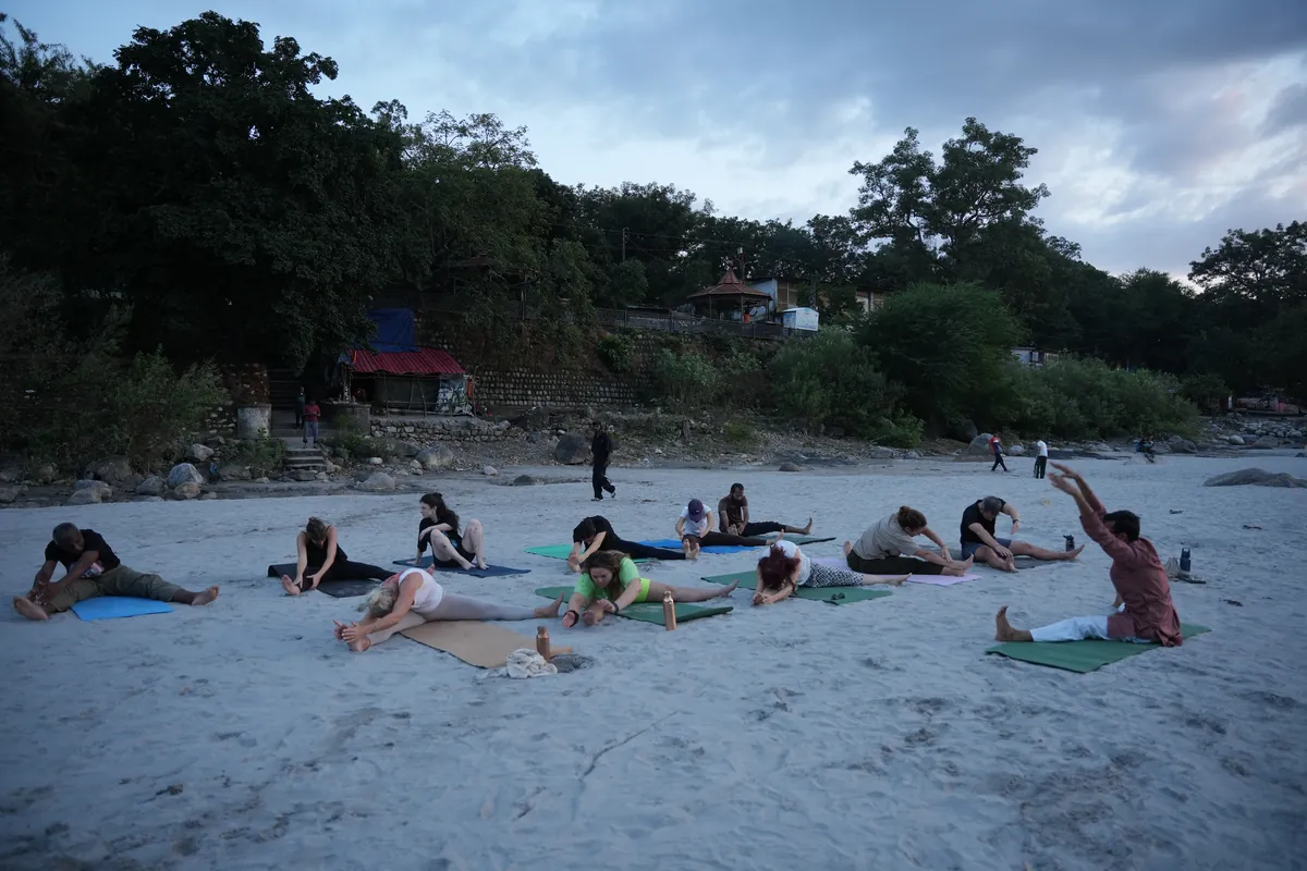 Ashtanga yoga teacher training group practising together on mats beside the river in Rishikesh