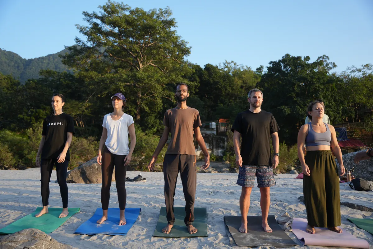 Ashtanga yoga teacher training students standing on their mats with the Himalayan foothills behind them