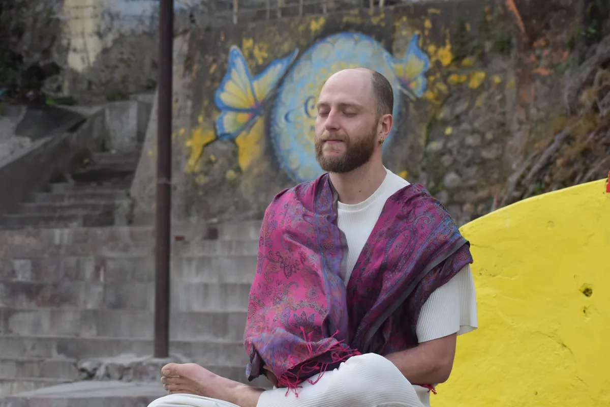 Student sitting in meditation against a painted wall in Rishikesh during kundalini training