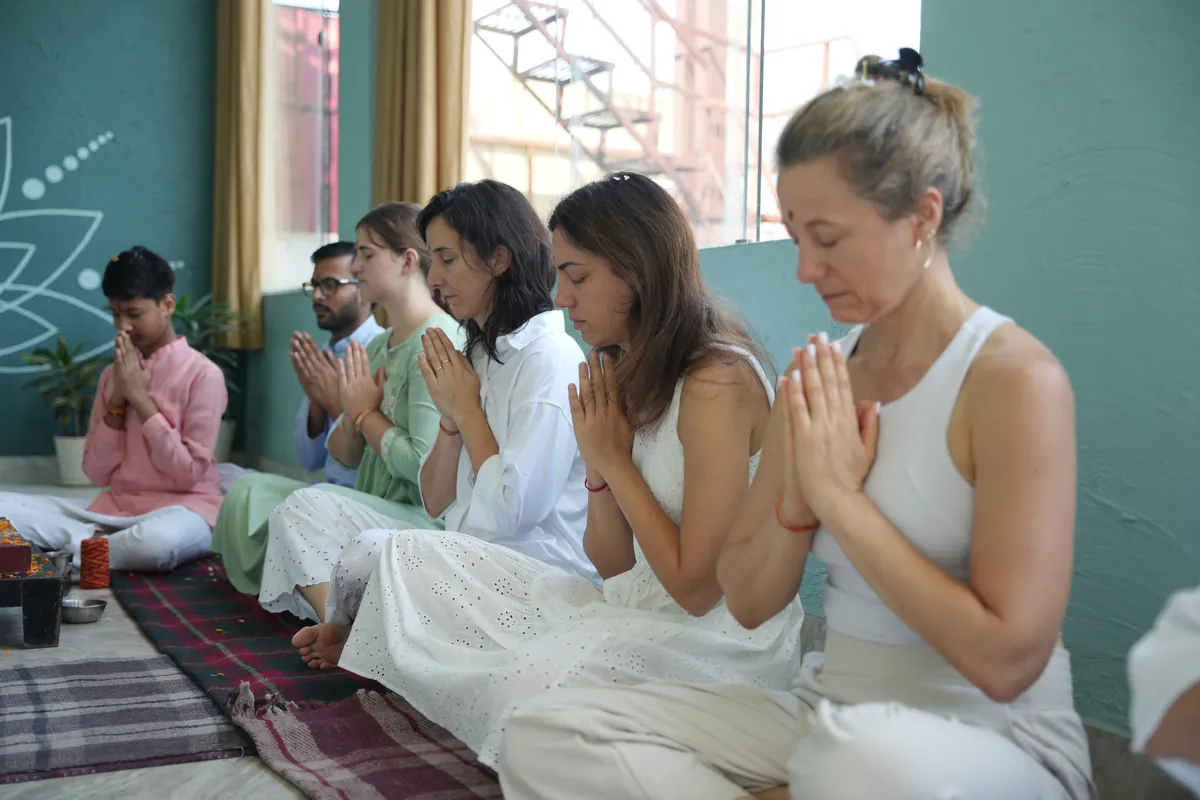 Meditation students sitting with hands in prayer position during a session in Rishikesh