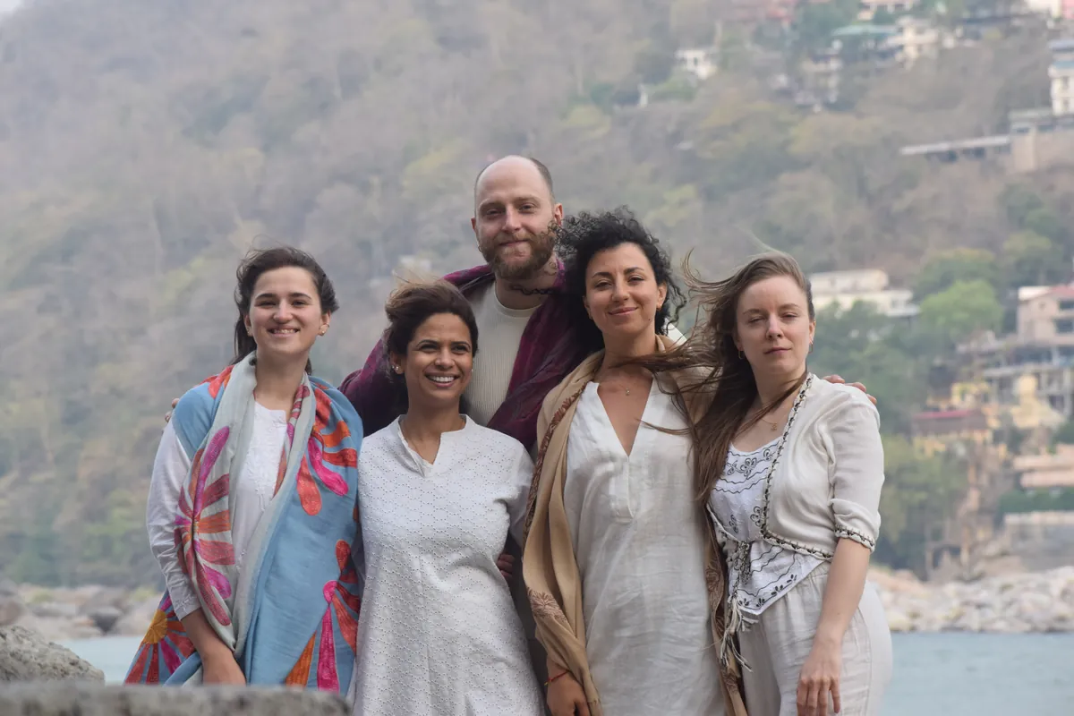 Yoga retreat group standing together with the Rishikesh hills and river behind them
