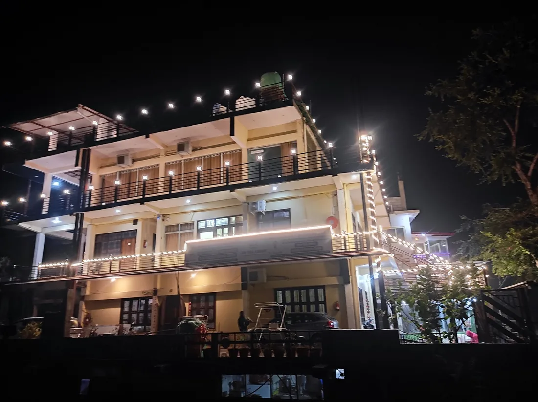 Ashram building in Rishikesh lit with string lights and balconies at night