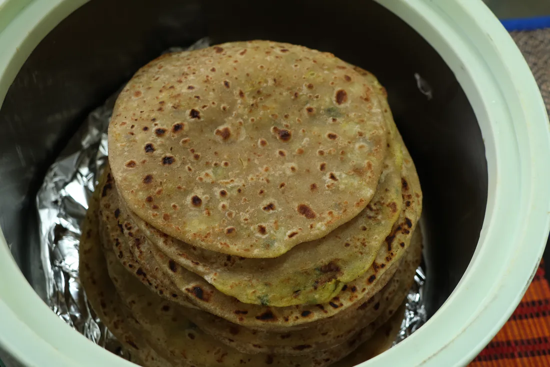 Stack of warm stuffed Indian flatbreads in a serving pot at Sri Yoga Ashram Rishikesh