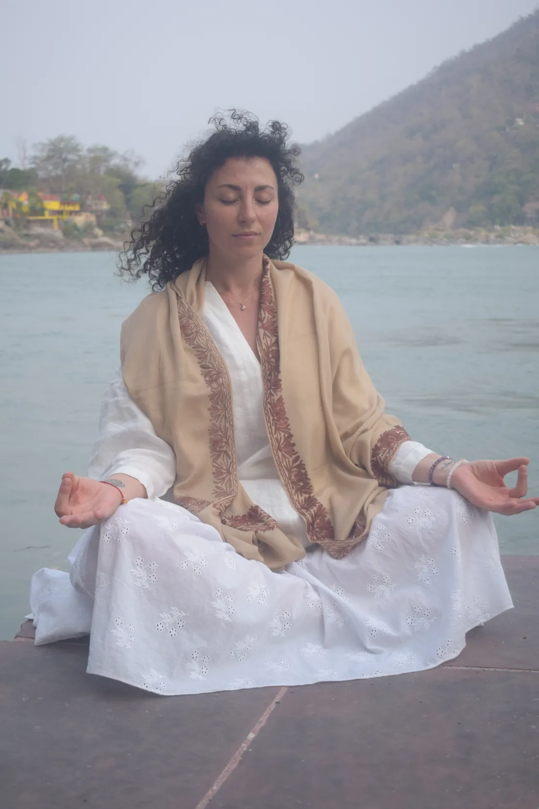 Guest meditating in lotus pose beside the Ganges during a Panchakarma stay in Rishikesh