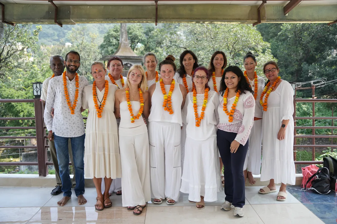 Yoga teacher training group wearing marigold garlands on a balcony at Sri Yoga Ashram Rishikesh